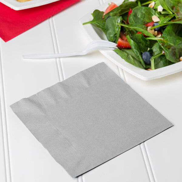 A plate of salad with a shimmering silver napkin and a fork.