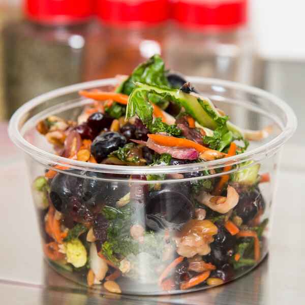 A salad in a Choice plastic deli container with carrots, cranberries, and blueberries.