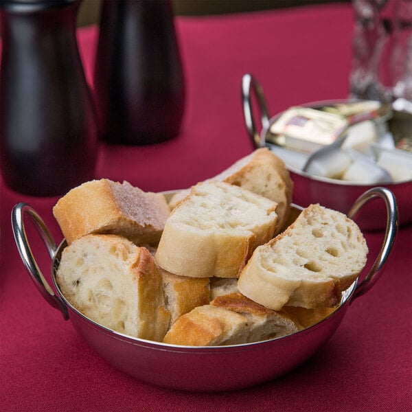 An American Metalcraft stainless steel balti dish with a piece of bread in it on a table.
