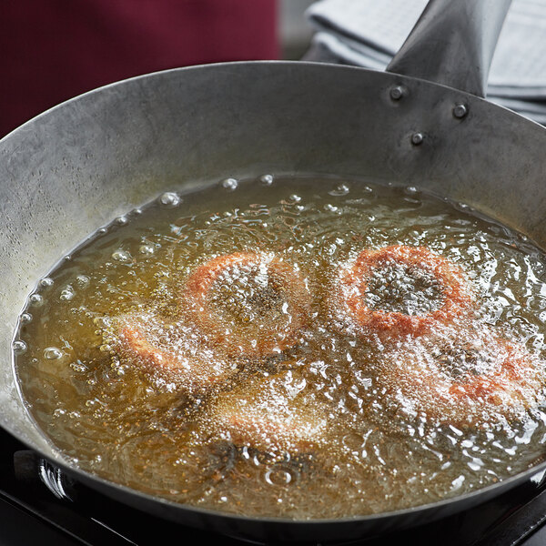 A frying pan of onion rings in Cottonseed Oil.