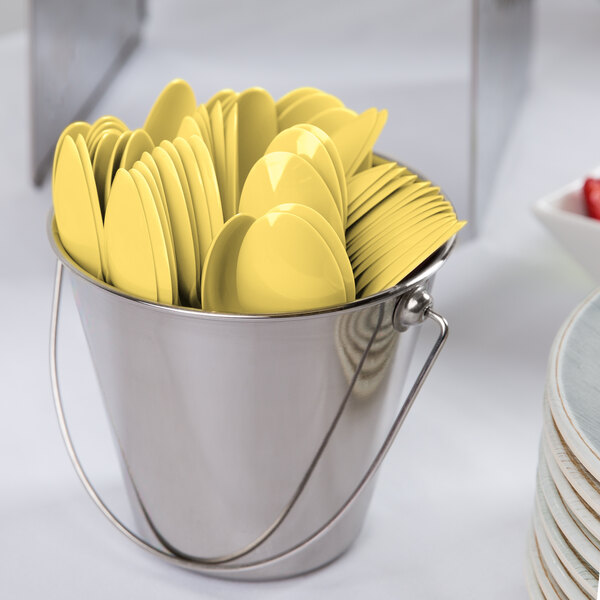 A bucket filled with yellow plastic spoons.