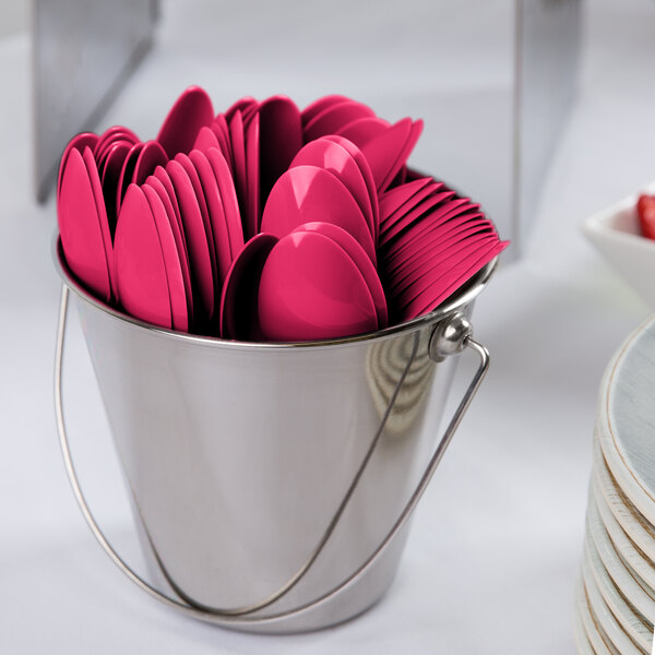 A bucket filled with hot magenta pink plastic spoons.