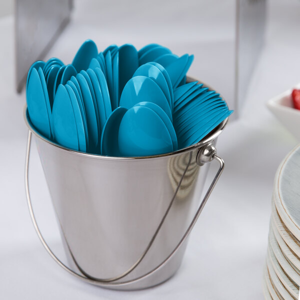 A bucket filled with turquoise blue plastic spoons.