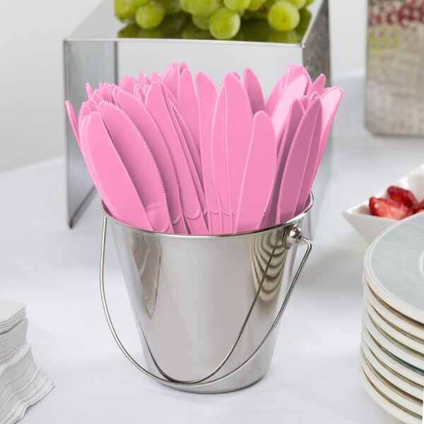 A bucket filled with pink Creative Converting plastic knives.
