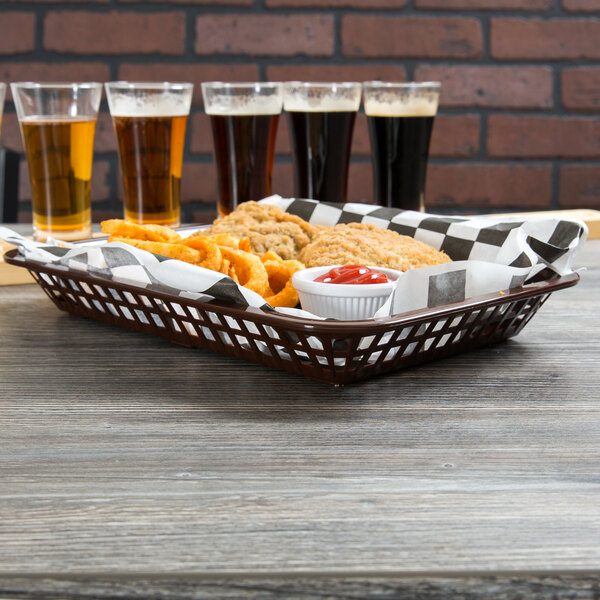 A Tablecraft brown plastic rectangular fast food basket on a table with food and drinks.