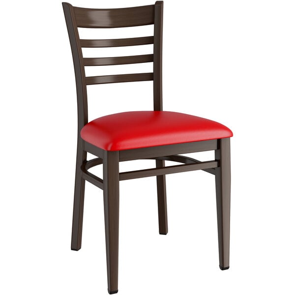 A Lancaster Table & Seating Spartan Series metal ladder back chair with a dark walnut wood grain finish and red vinyl seat.