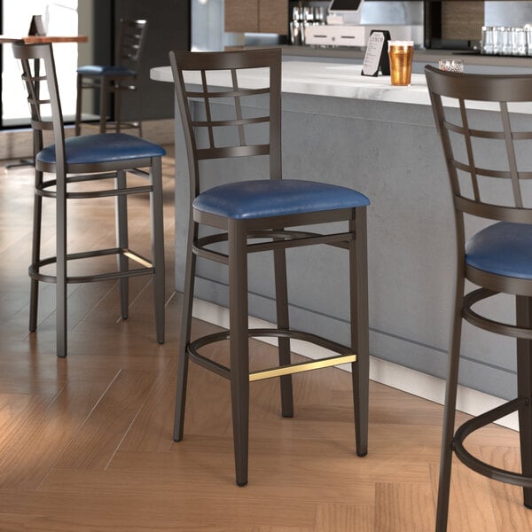 A Lancaster Table & Seating bar stool with a navy vinyl seat and dark walnut wood grain finish.