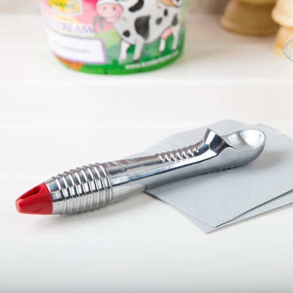 A Vollrath aluminum ice cream scoop with a red end on a napkin.