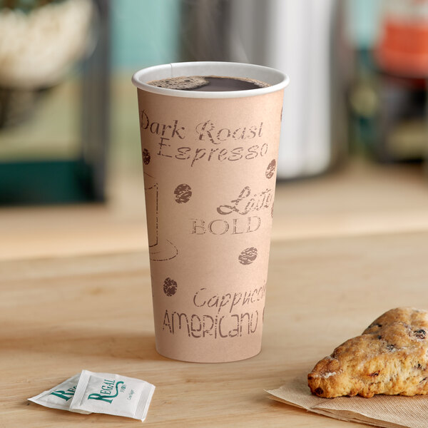 A Choice 20 oz. caf&#233; print paper hot cup on a counter with a cup of coffee and a pastry.