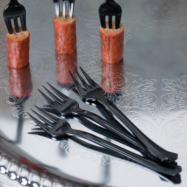 A silver tray with a hotdog and black WNA Comet Petite tasting forks.