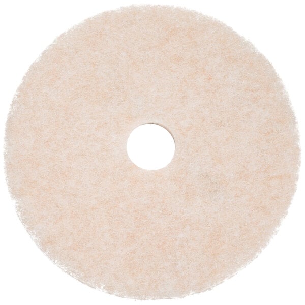 A white circular 3M burnishing pad with a hole in the middle.