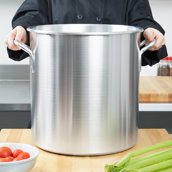 A chef holding a large Vollrath aluminum stock pot.