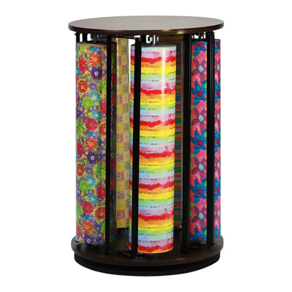 A Bulman walnut Suzy rack holding rolls of colorful wrapping paper on a round wooden stand.