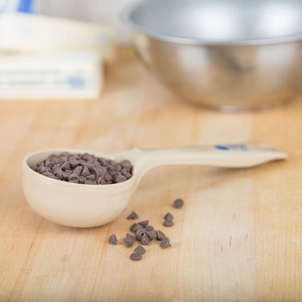 A Carlisle beige portion spoon filled with chocolate chips.