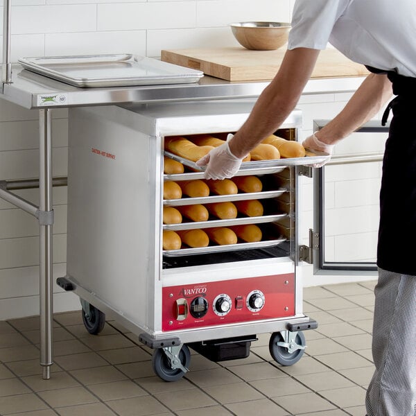 A man using an Avantco undercounter heated holding / proofing cabinet to put bread in.