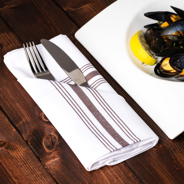 A plate of mussels with a fork on a chocolate striped Snap Drape Softweave napkin on a wooden table.