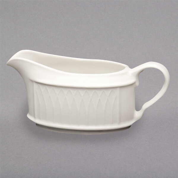 A Homer Laughlin ivory sauce boat with a curved design and a handle.