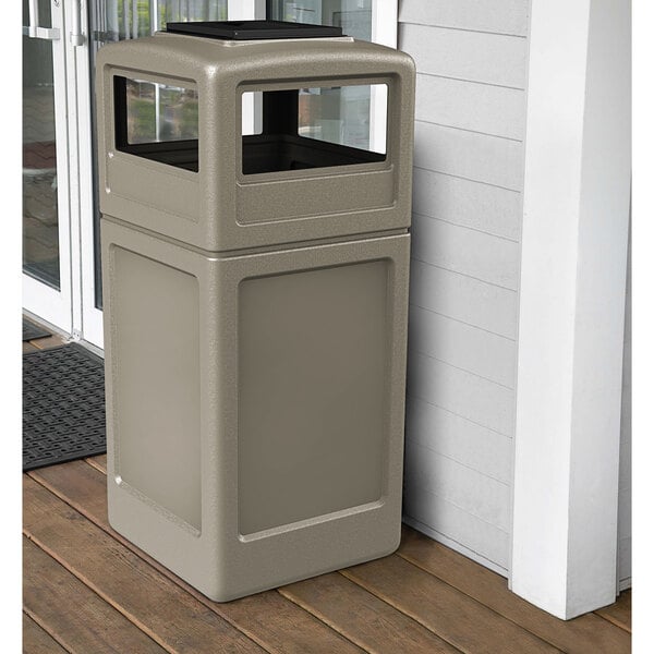 A beige rectangular waste container with an ashtray dome lid on a porch.