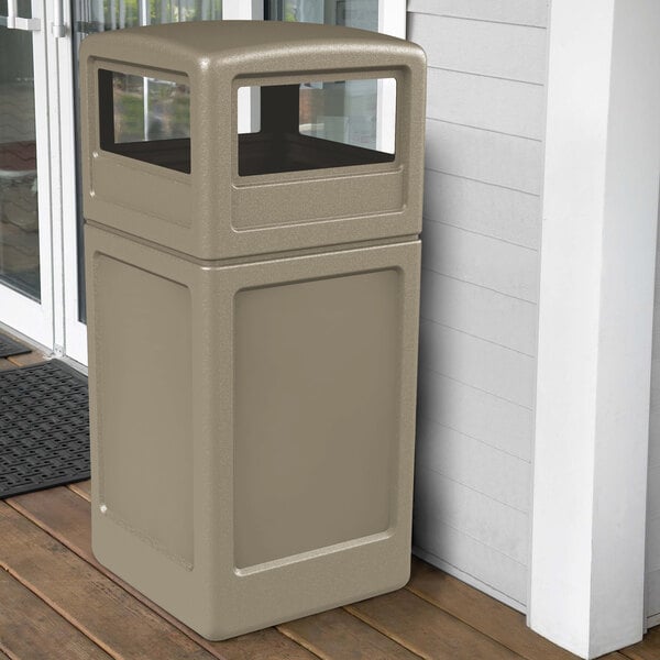 A tan Commercial Zone PolyTec rectangular waste container and dome lid on a porch.