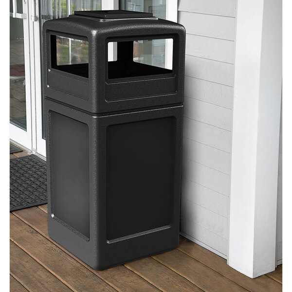 A black Commercial Zone PolyTec waste container with a square top and ashtray lid on a porch.