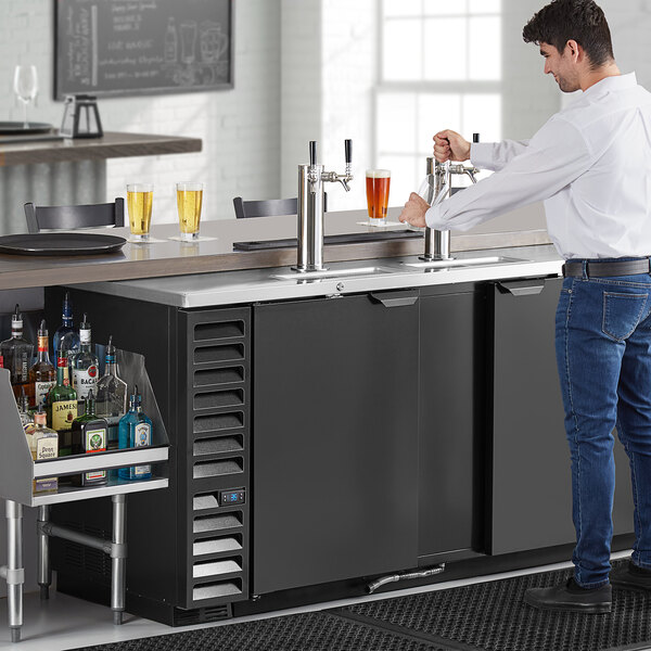 A man pouring beer from a Beverage-Air black double tap kegerator.