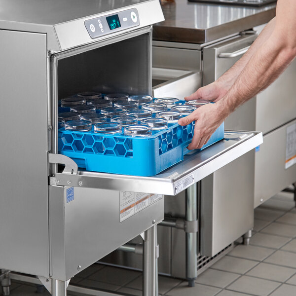 A person putting a blue container into a Hobart high temperature glass washer.