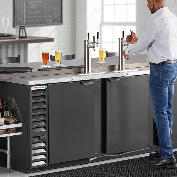 A man using a Beverage-Air triple tap kegerator to pour a beer.