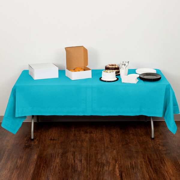 A table with Bermuda Blue Creative Converting table cover and food on it.