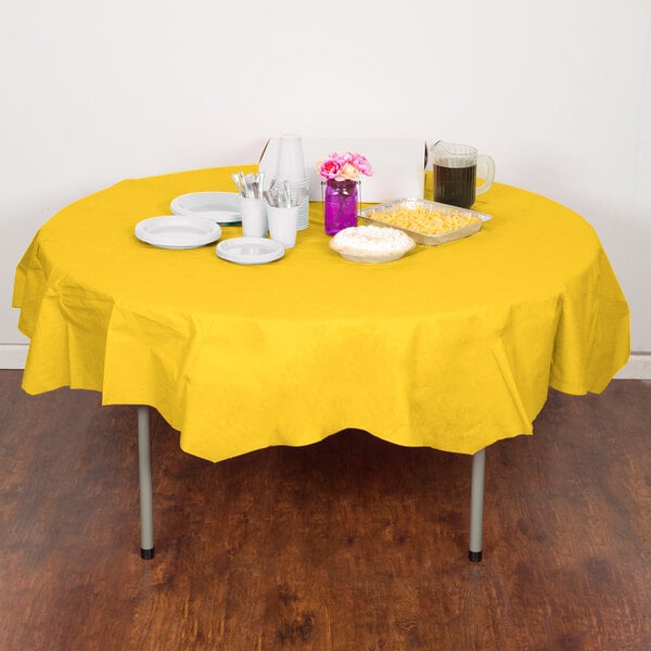 A table with a School Bus Yellow OctyRound table cover with plates and cups on it.