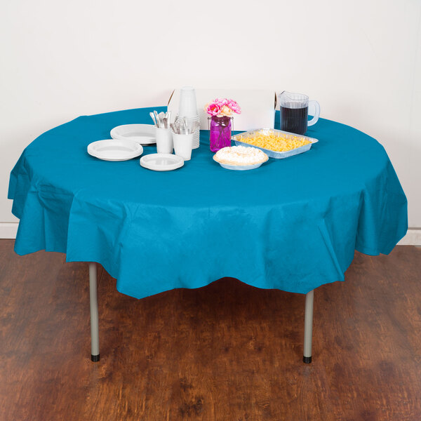 A table with a turquoise blue tablecloth, plates, and cups.