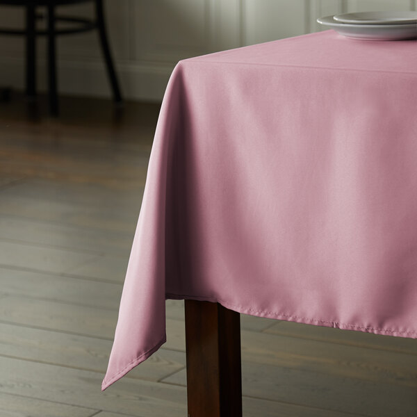 A table with a pink Intedge 100% polyester hemmed table cloth.
