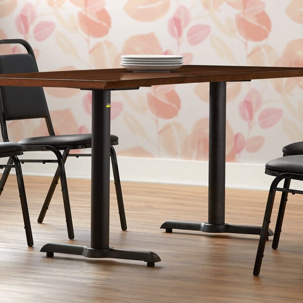 A FLAT Tech black end table base set on a table with plates and chairs in a restaurant dining area.