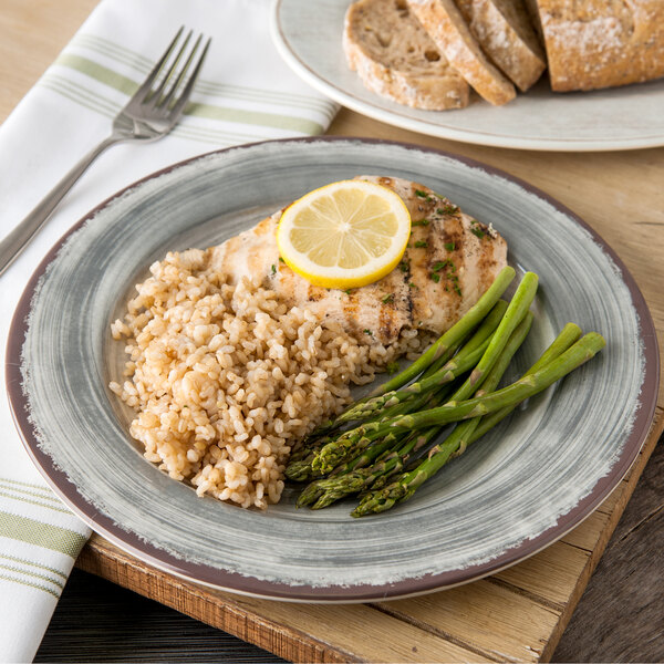 A Carlisle Mingle smoke melamine plate with rice, asparagus, and chicken with a lemon wedge on top.