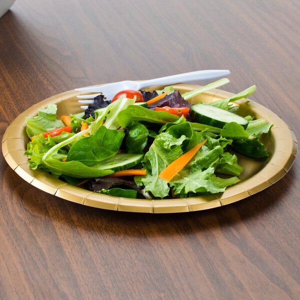 A Creative Converting glittering gold paper plate with salad on a table.