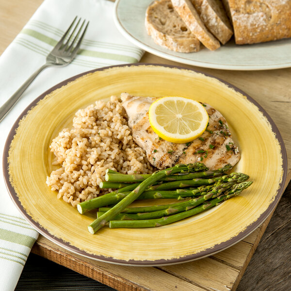 A Carlisle Mingle melamine plate with rice, asparagus, and chicken with a lemon slice on the side.