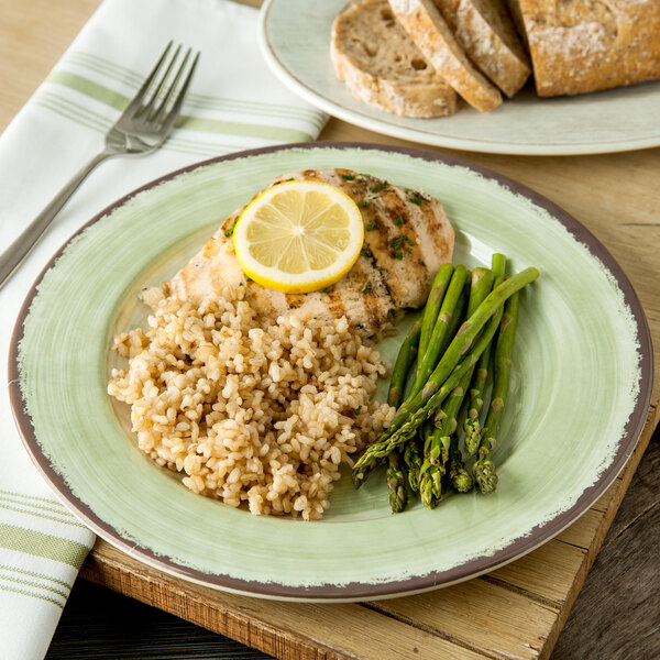 A Carlisle jade melamine plate with asparagus, rice, and chicken with a lemon wedge on top.