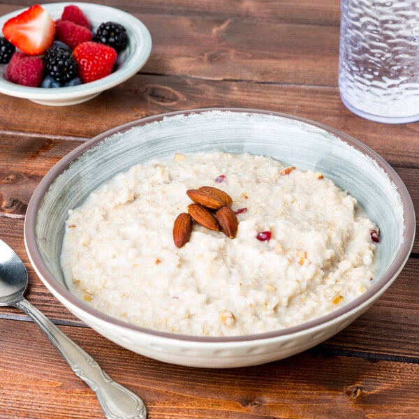 A Carlisle smoke melamine bowl filled with oatmeal, almonds, and berries on a white table.