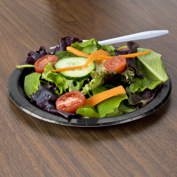 A plate of salad with a black velvet paper plate and a fork.