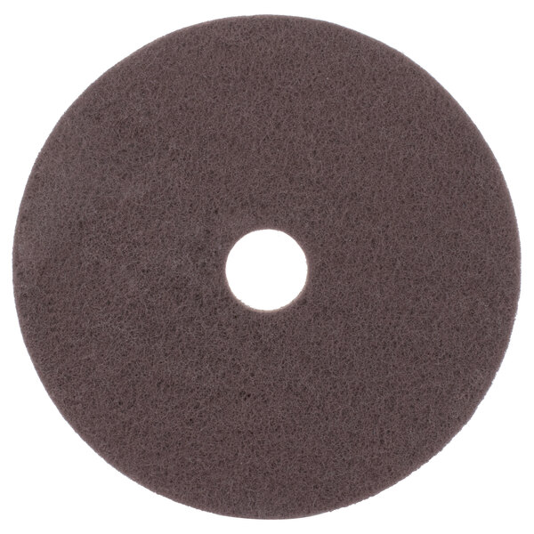 A brown circular 3M stripping floor pad with a hole in the middle.