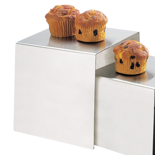 A group of muffins on a stainless steel cube riser.