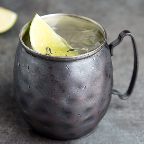 A World Tableware hammered antique copper Moscow Mule mug filled with a lime wedge.