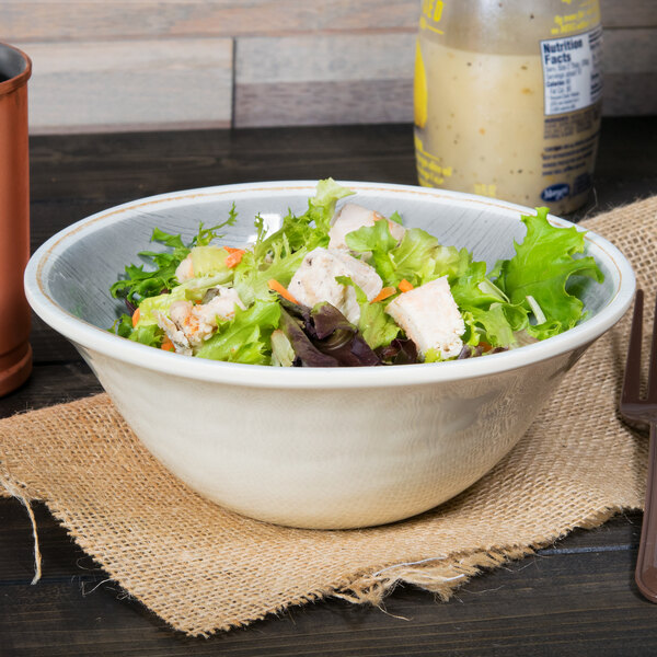 A Carlisle smoke melamine bowl filled with salad on a table.
