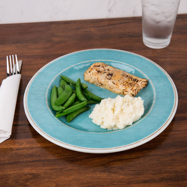 A Carlisle Grove aqua melamine plate with a piece of fish, mashed potatoes, and green beans on it.