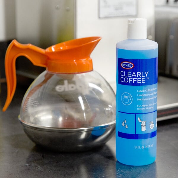 A blue bottle of Urnex Clearly Coffee liquid next to a coffee pot.