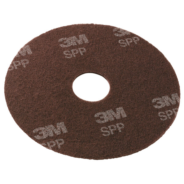 A brown 3M Scotch-Brite surface preparation pad with a hole in the middle.