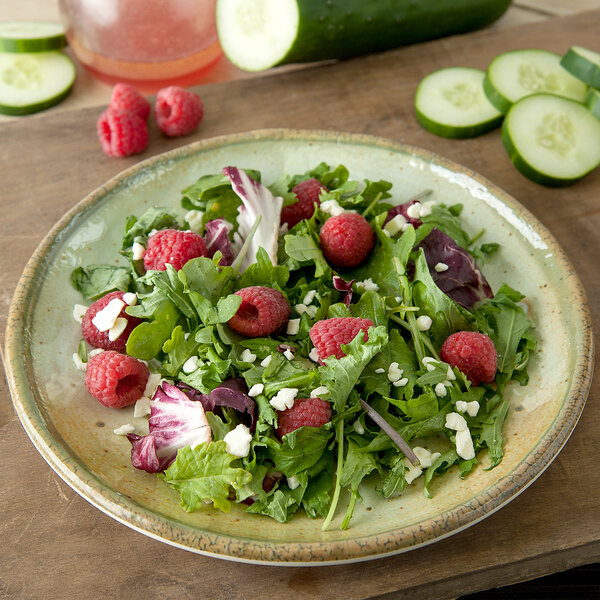 A Carlisle round melamine salad plate with a salad of raspberries and cucumbers.