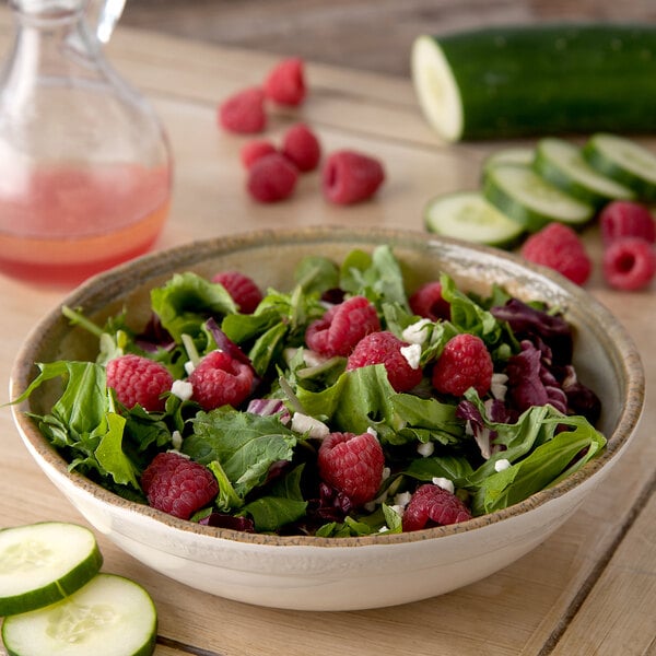 A Carlisle adobe melamine bowl filled with salad with raspberries, cucumbers, and feta.