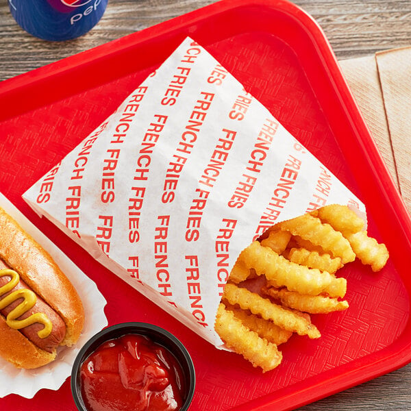 A red tray with a hot dog and fries in a Carnival King extra large French fry bag.