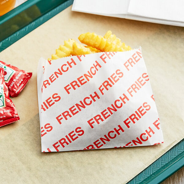 A tray of Carnival King large French fry bags on a table with french fries and ketchup.