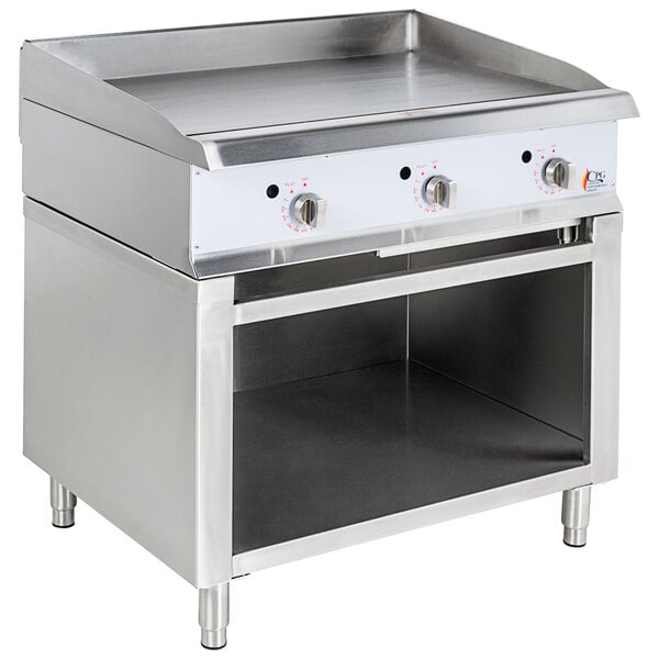 A Cooking Performance Group stainless steel gas griddle with knobs on a cabinet base.